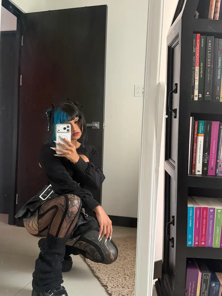 Vesper crouching in black boots and fishnets